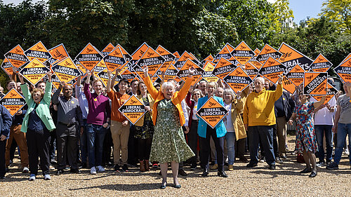 Charlotte Cane in front of a large group of people wih Liberal Democrat poster boards