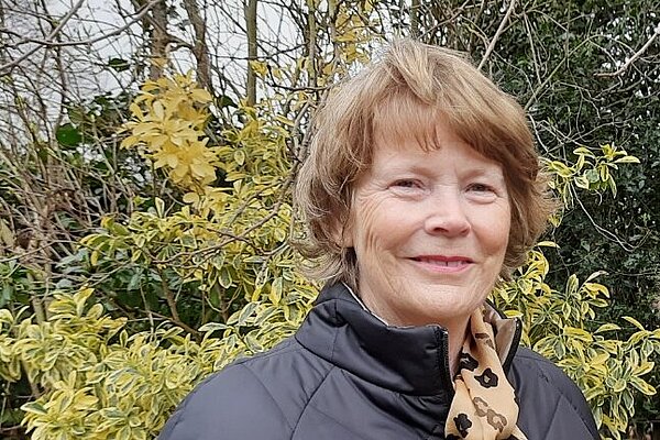 Caroline Shepherd, head and sholders shot, stood in front of yellow leafed bush