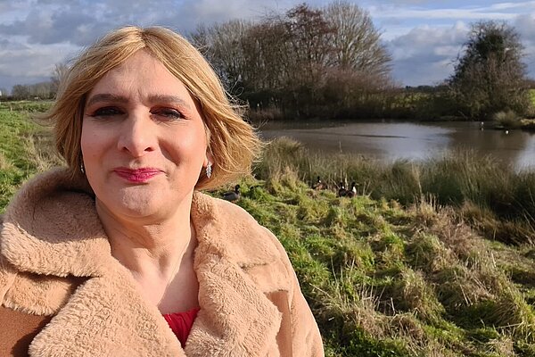 Sarah March head and shoulders image alongside a river with tress in the distance