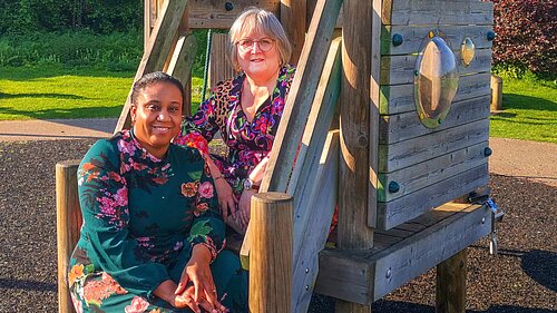 Chika Akinwale and Lorna Dupre sitting on equipment at a childrens playpark