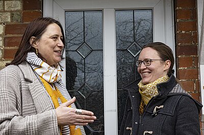 Mary Wade and Kathrin Holtzmann talking in front of house door