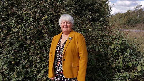 Charlotte Cane standing next to a hedge